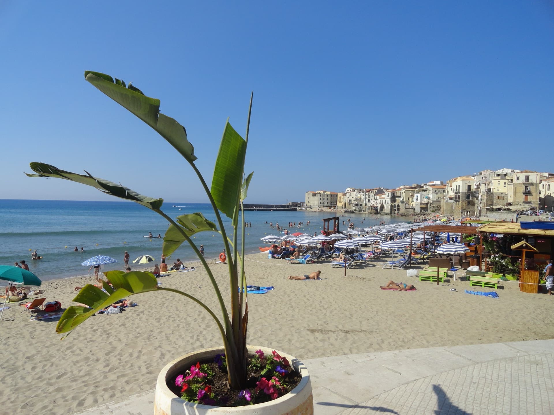 Plage ensoleillée de Cefalù avec maisons anciennes au bord de la mer